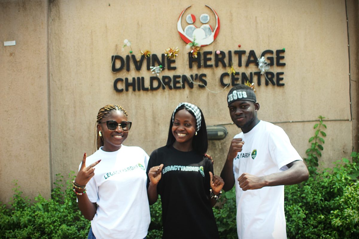 Three LYHF team members in front of the Divine Heritage Children's Centre sign