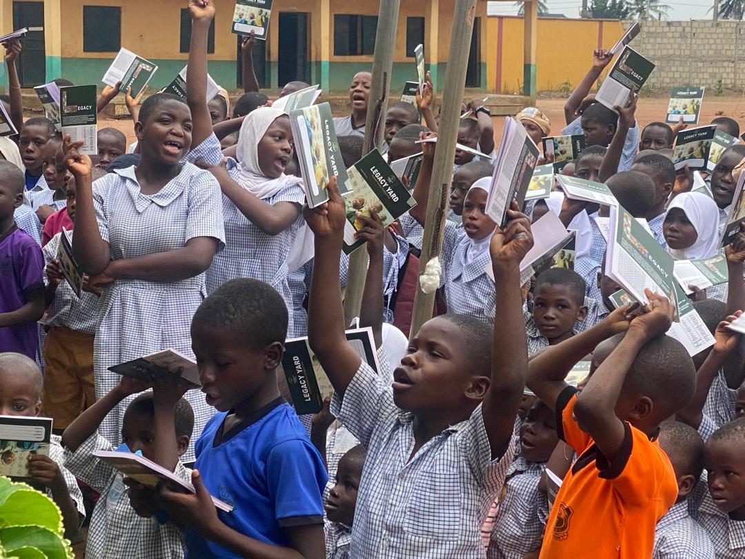 Pupils cheering with Legacy Yard exercise books raised