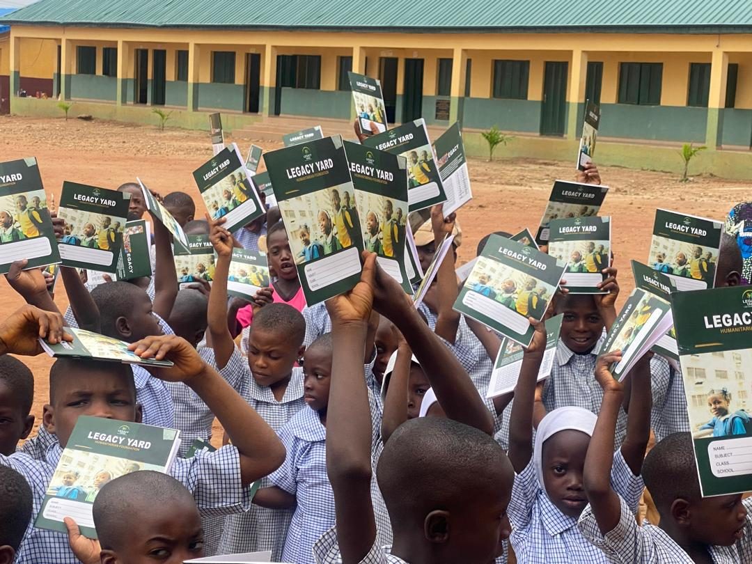 Rows of pupils holding exercise books in front of classrooms